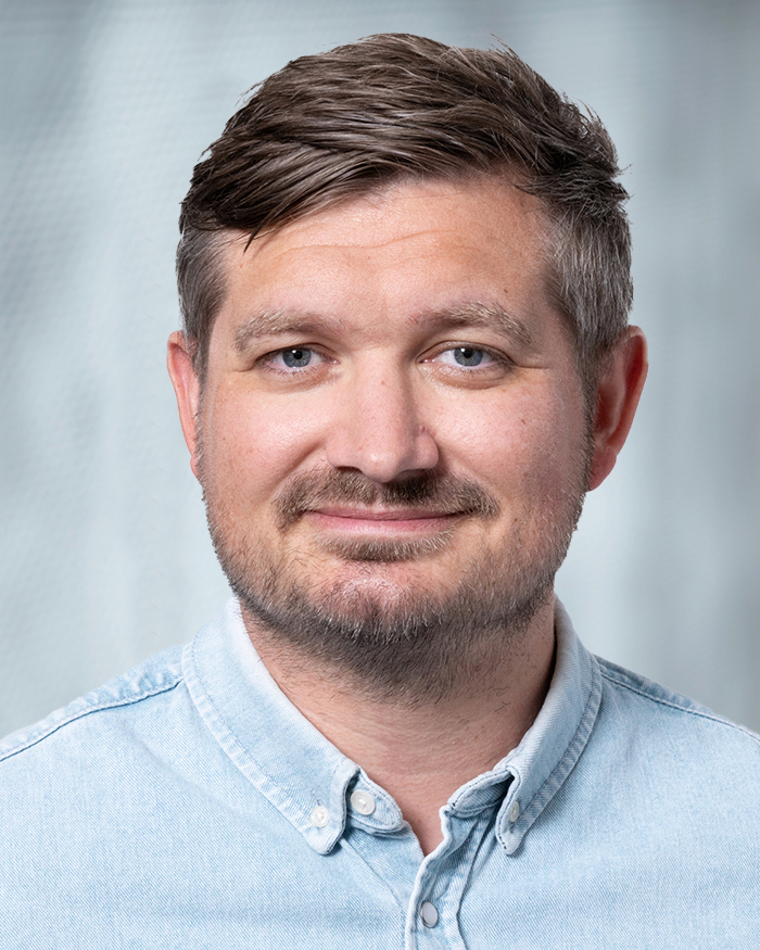 Portrait Benjamin Börner, männlich lesbare, weisse Person mit kurzen Haaren, Bart und hellblauem Hemd